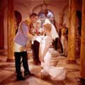 Milton H Greene took this color image of Marilyn Monroe and Sir Laurence Olivier during the filming of The Prince and The Showgirl in 1956. Marilyn is wearing a white wedding gown and veil while kneeling before Olivier. Laurence is wearing military regalia and looking serious.