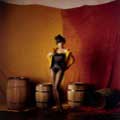 Wearing a bustier and stockings, Diahann Carroll is playful in her yellow fitted jacket and top hat with wooden barrels in the background. This 1960 image by Milton H Greene was taken during Diahann's album cover session.
