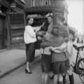 Milton Greene took this vintage Irish fashion photograph while on assignment for Life Magazine in 1953. Model Lisa Fonssagrives stands at a bread cart wearing a bandanna and a cute white jacket while holding bread and looking playfully at a group of children gathered to the right. Milton was in Ireland photographing rising designer Sybil Connelly.