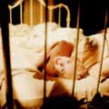 Milton H. Greene captures a famous color photo of Marilyn Monroe in her classic 1956 movie of Bus Stop. Marilyn Monroe is seen in bed laying on her side looking back seductively through the bed rails smiling with white sheets and linen draping her nude body.